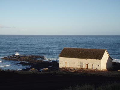 Photo of the plumbing and electrical shop, a white building on rocky shore.